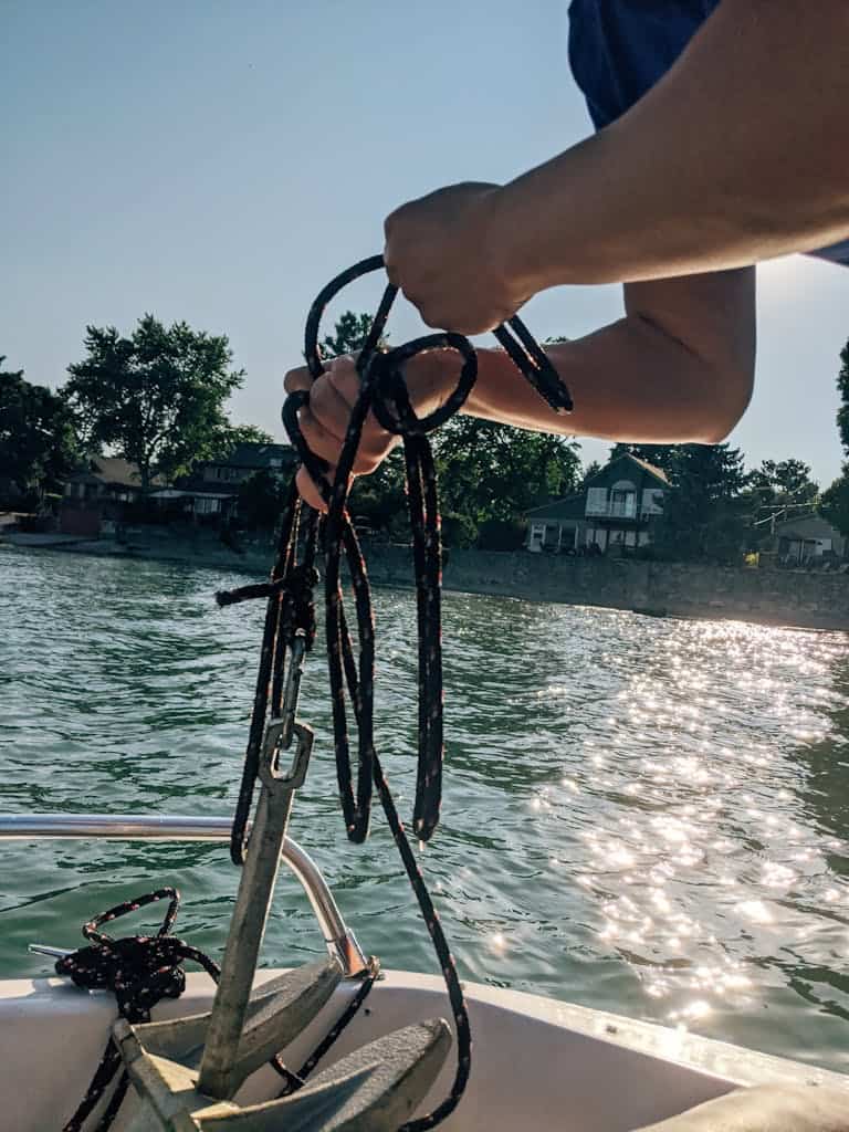 Crop person with anchor on boat in sea