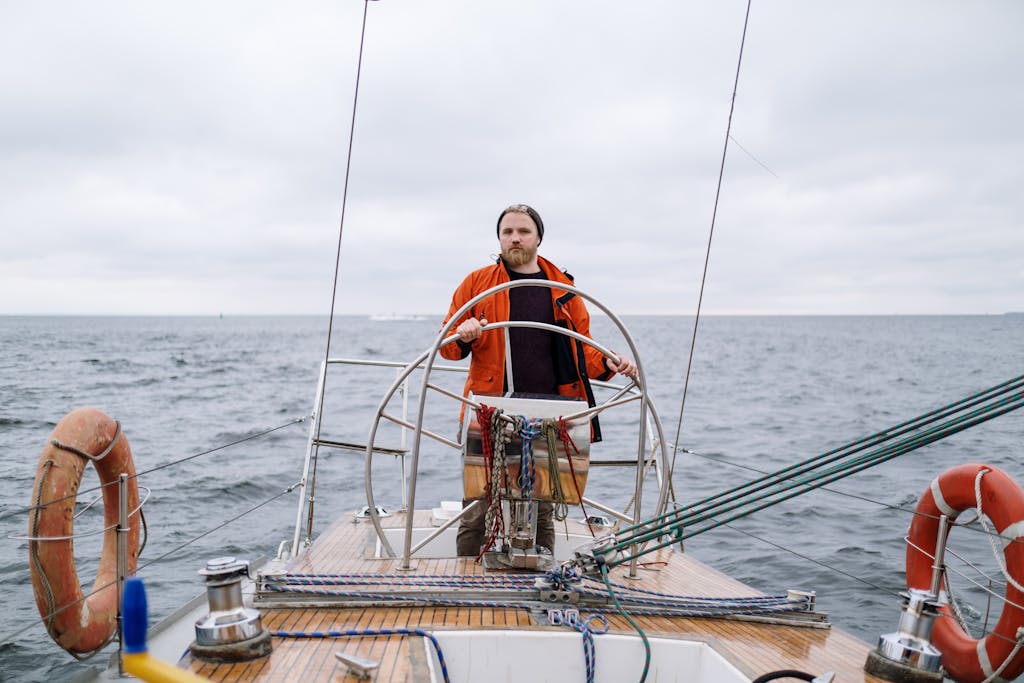 Man in Orange Jacket Sailing on a Boat