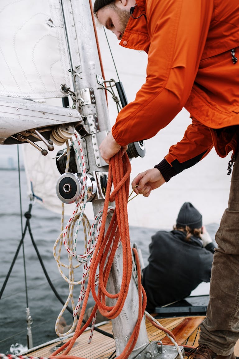 Man in a Jacket Fixing the Ropes on the Ship